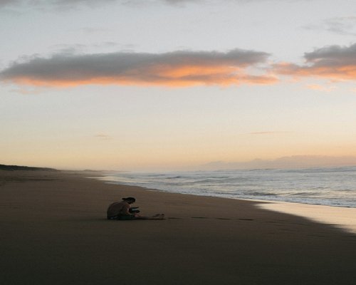 A person meditating by the ocean at sunrise